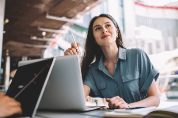 Millennial woman looking in the distance with a pen in her hand