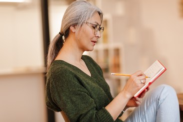Woman sitting on a sofa writing in a journal