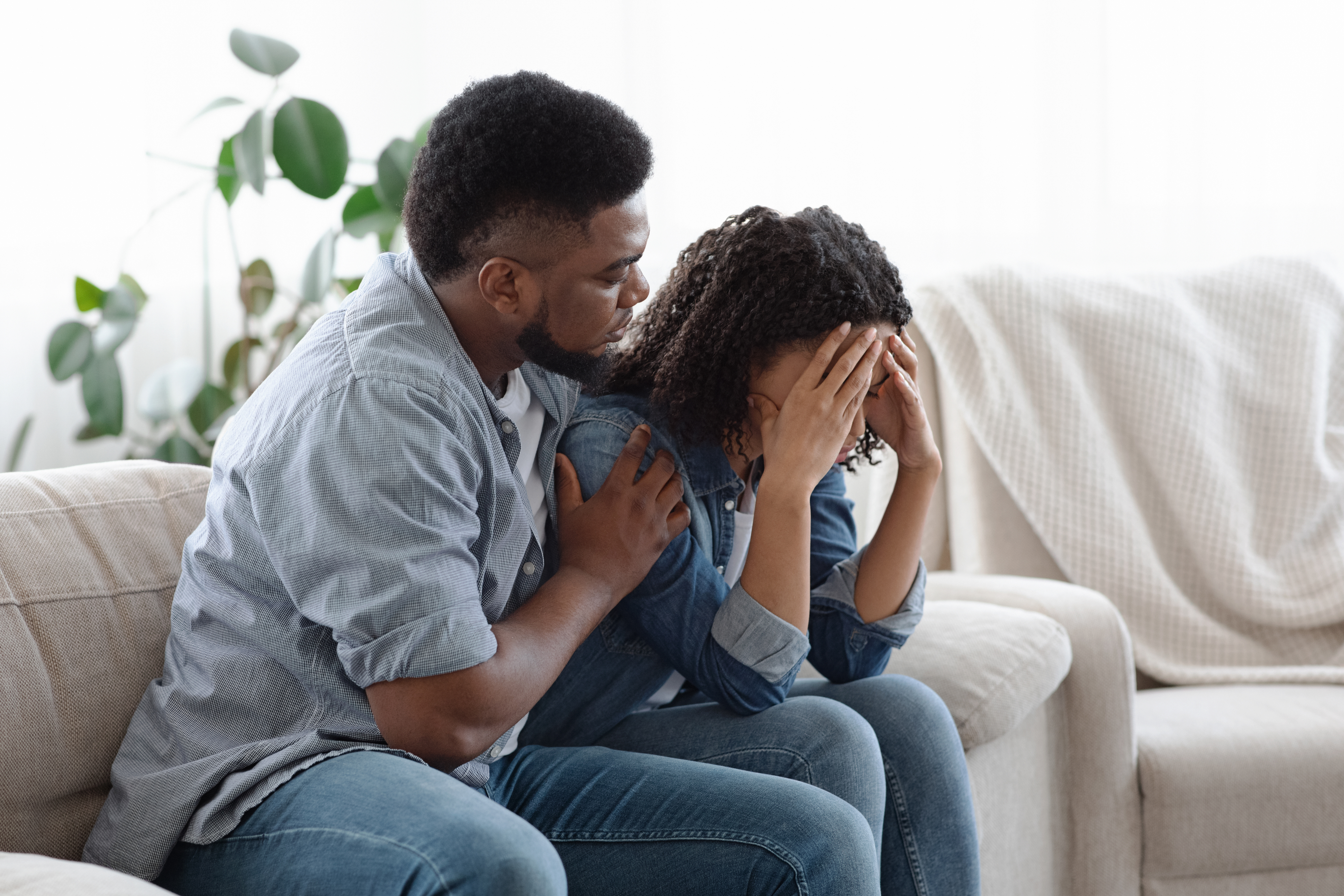 Man comforting a woman crying on the sofa.