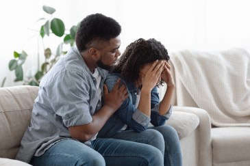 Man comforting a woman crying on the sofa.