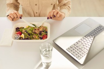 Woman eating a salad while at her desk