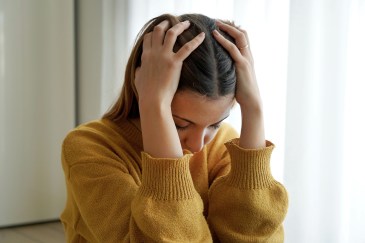 Woman holding her head in her hands while looking downward