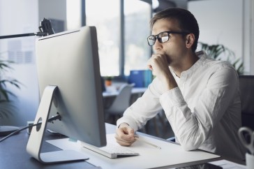 Man with glasses looking at computer