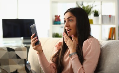 Woman looking surprised holding phone
