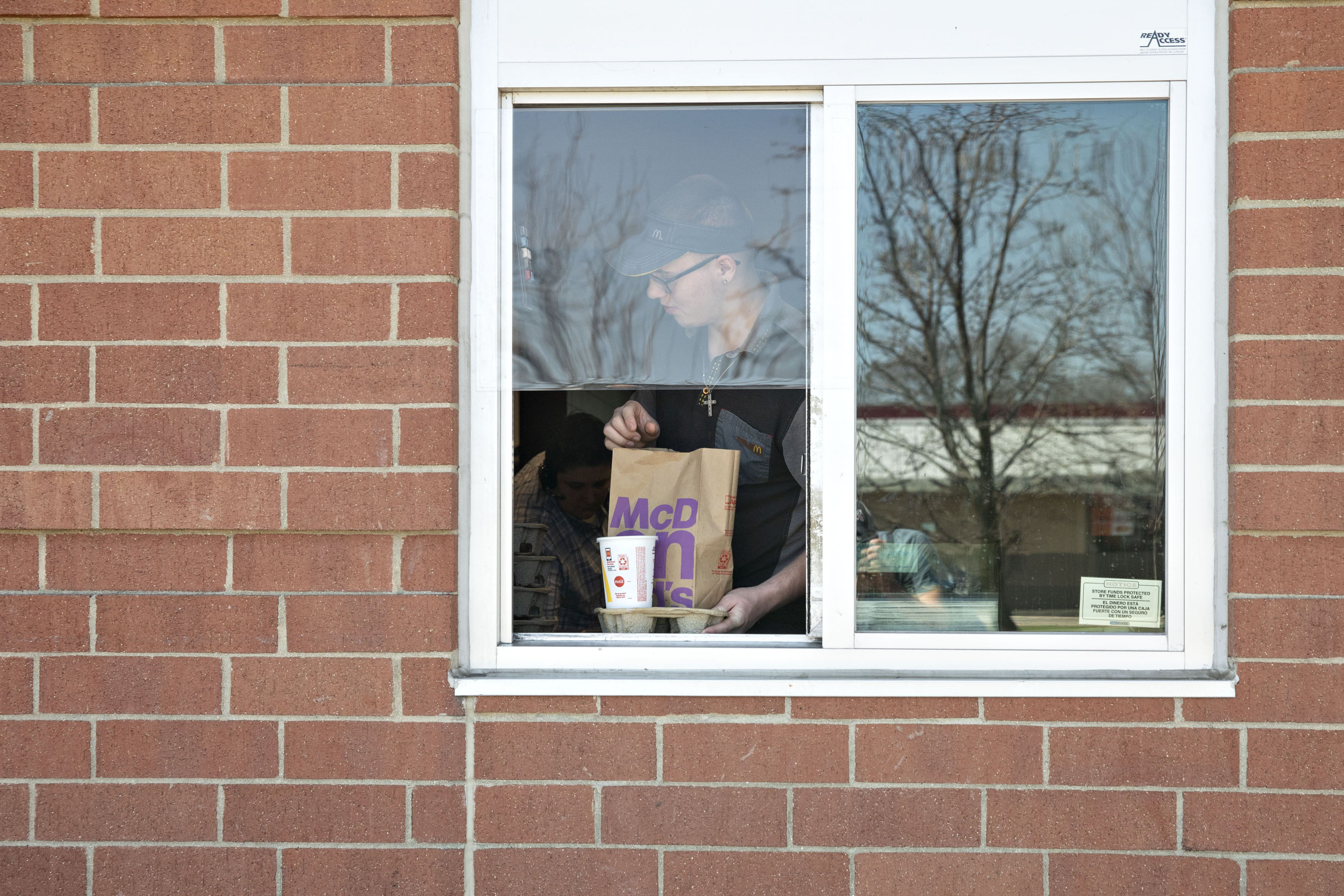 A McDonald's employee is handing out food in a drive-thru window.