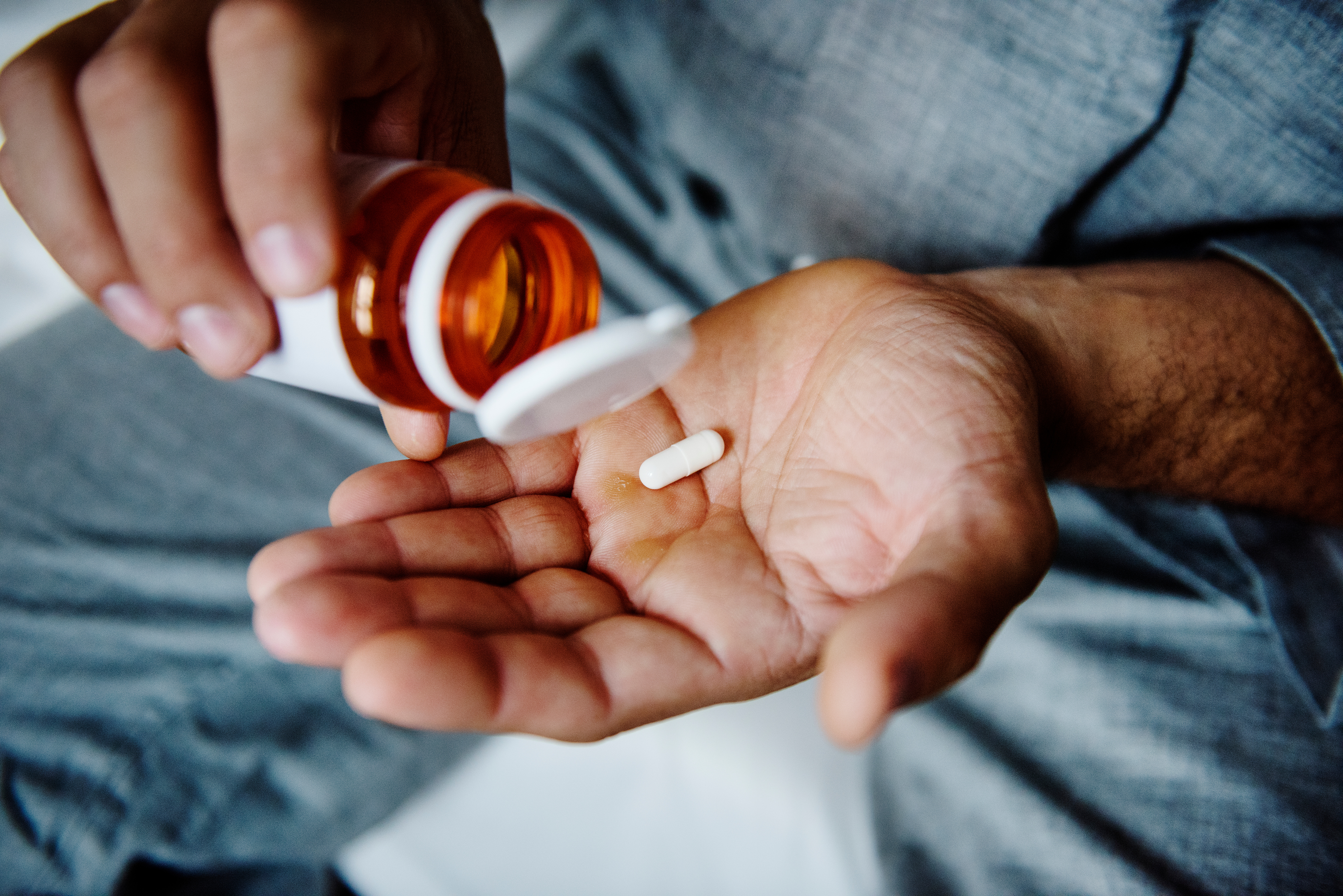 Man putting a pill from a bottle into his hand