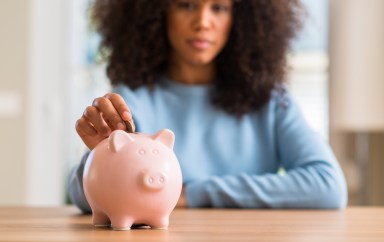 Woman putting a coin into a piggy bank
