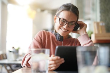 Millennial woman looking at an iPad with headphones on