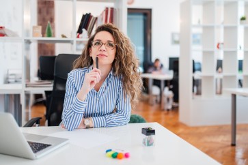 Woman thinking of ideas while sitting at her desk