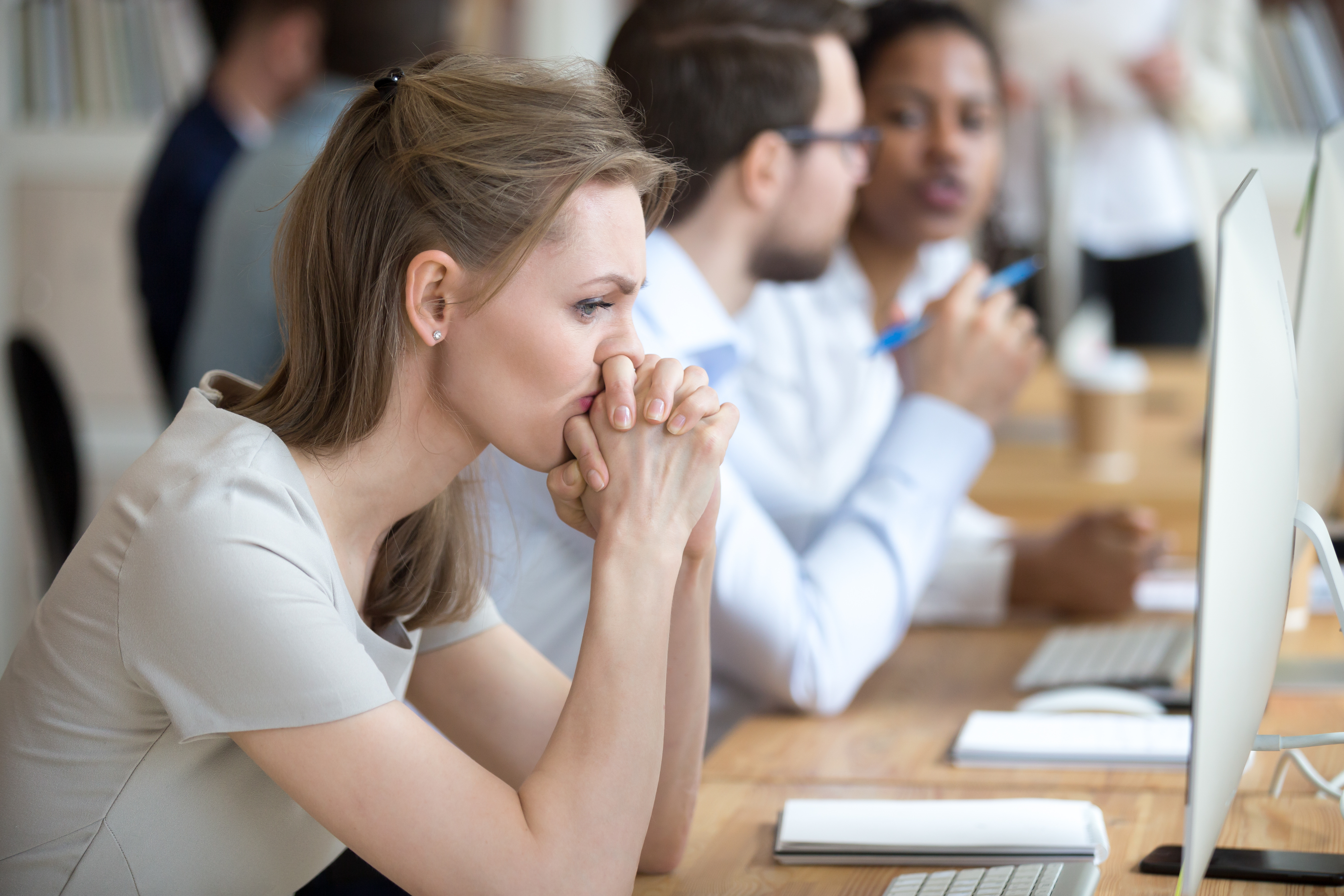 Uncertain or preoccupied female employee with hands clasped
