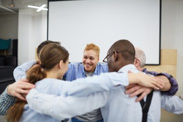 A group of employees embracing in a meeting room
