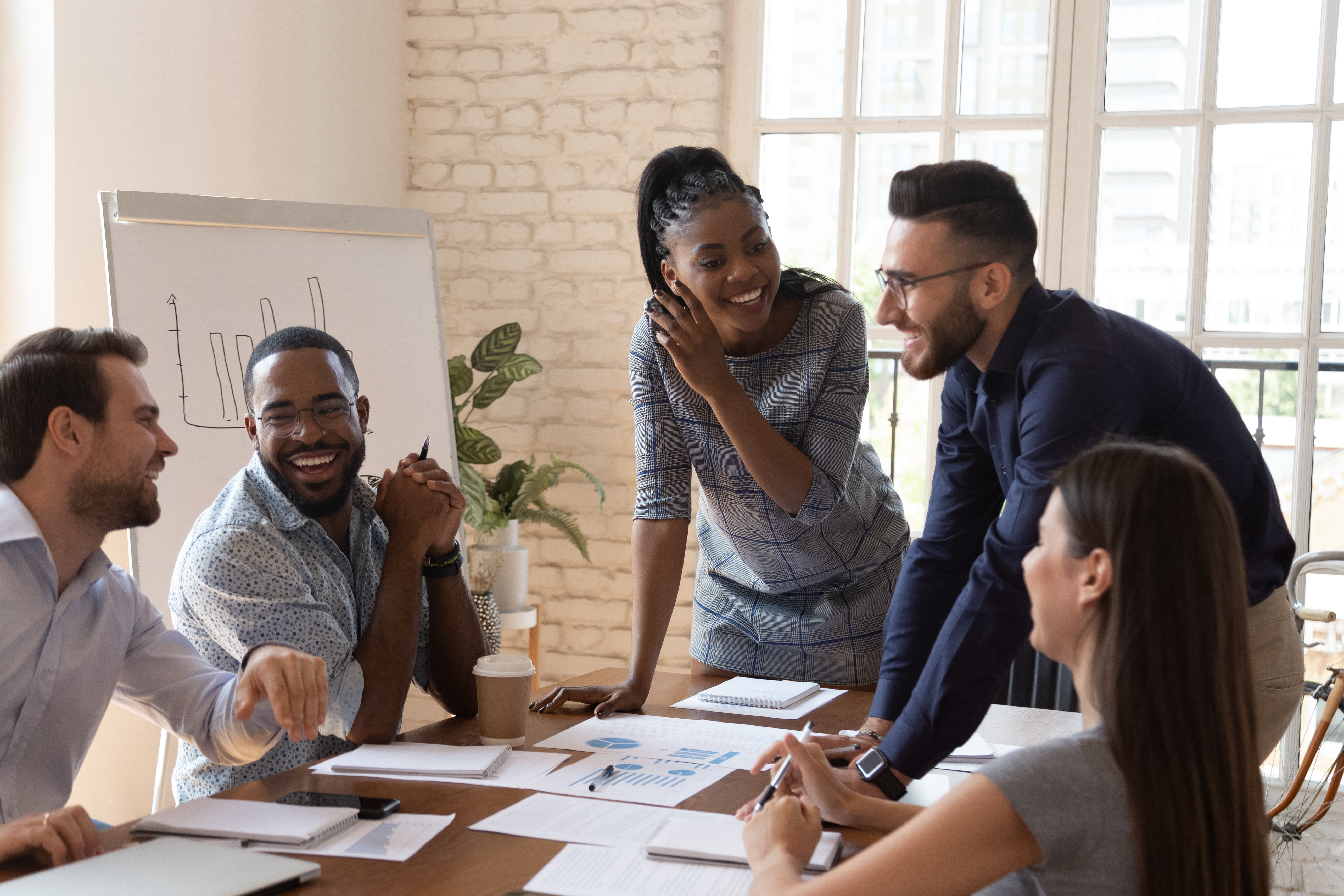 Employees laughing and talking around table at work