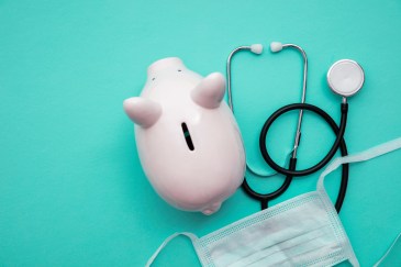 An overhead view of a piggy bank with medical supplies around it