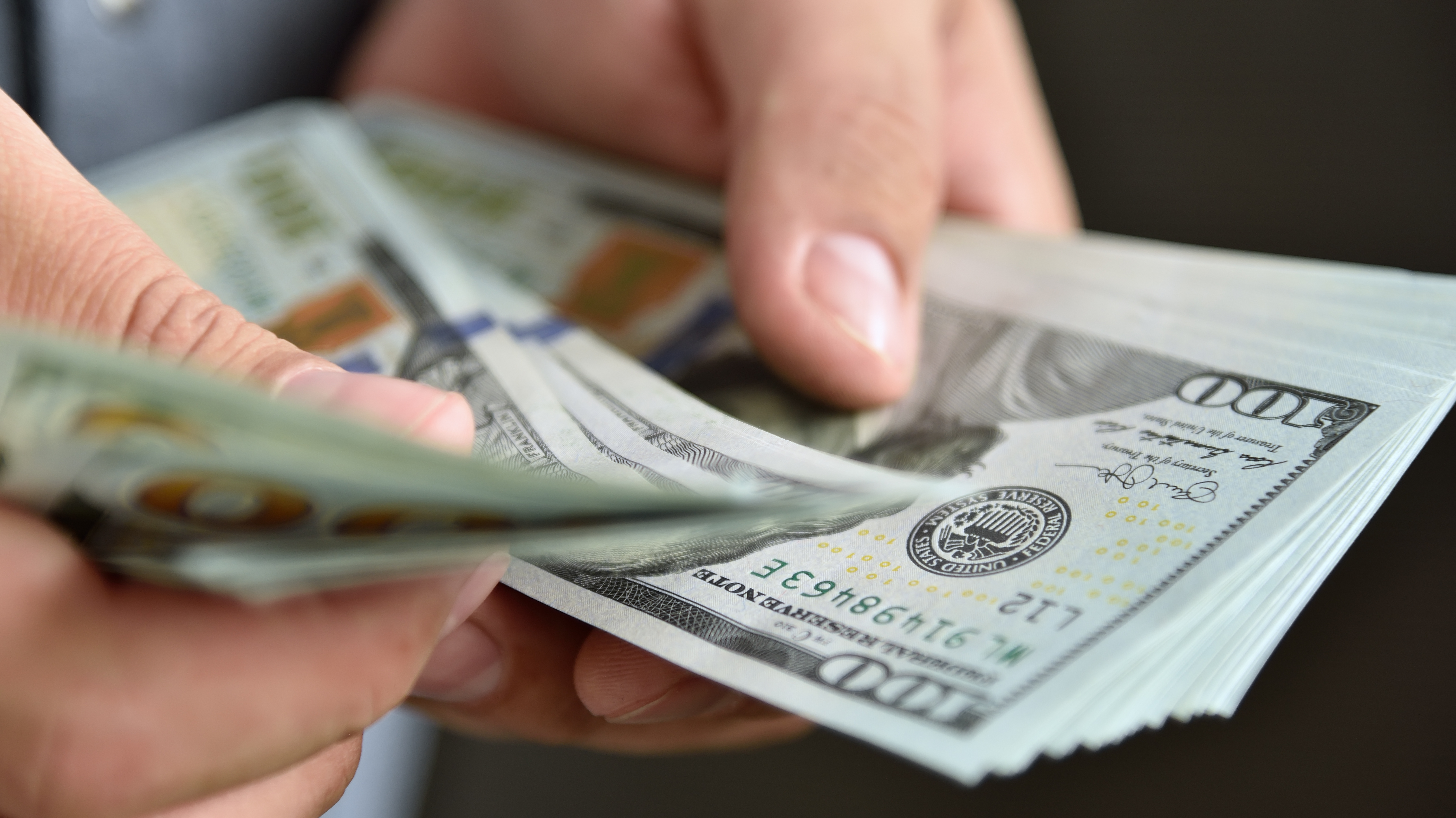 Man counting a stack of $100 bills