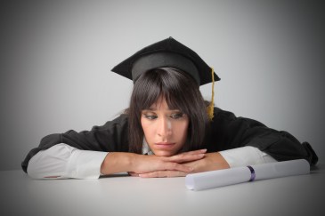 Woman college graduate looking at diploma sad