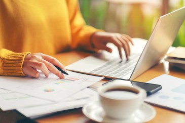 Woman in yellow sweater working on laptop
