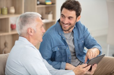 Parent with adult son looking at computer and talking