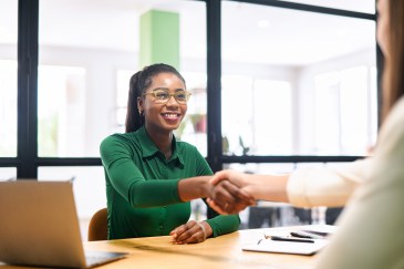 Woman shaking hands across desk in job interview