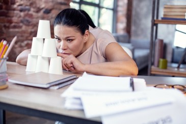 Woman stacking cups instead of doing work at her desk