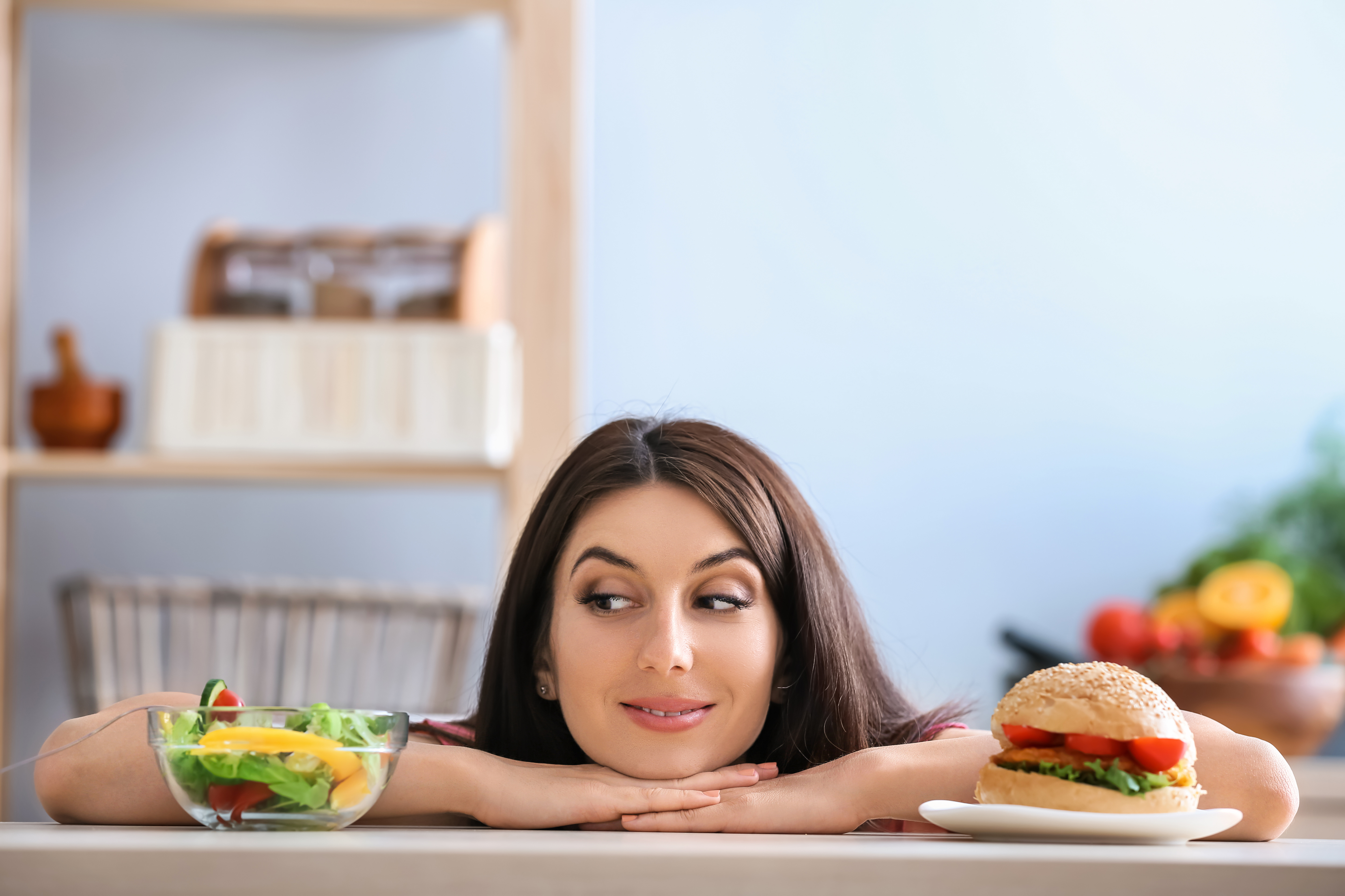 Woman choosing between salad and burger; choosing healthy food