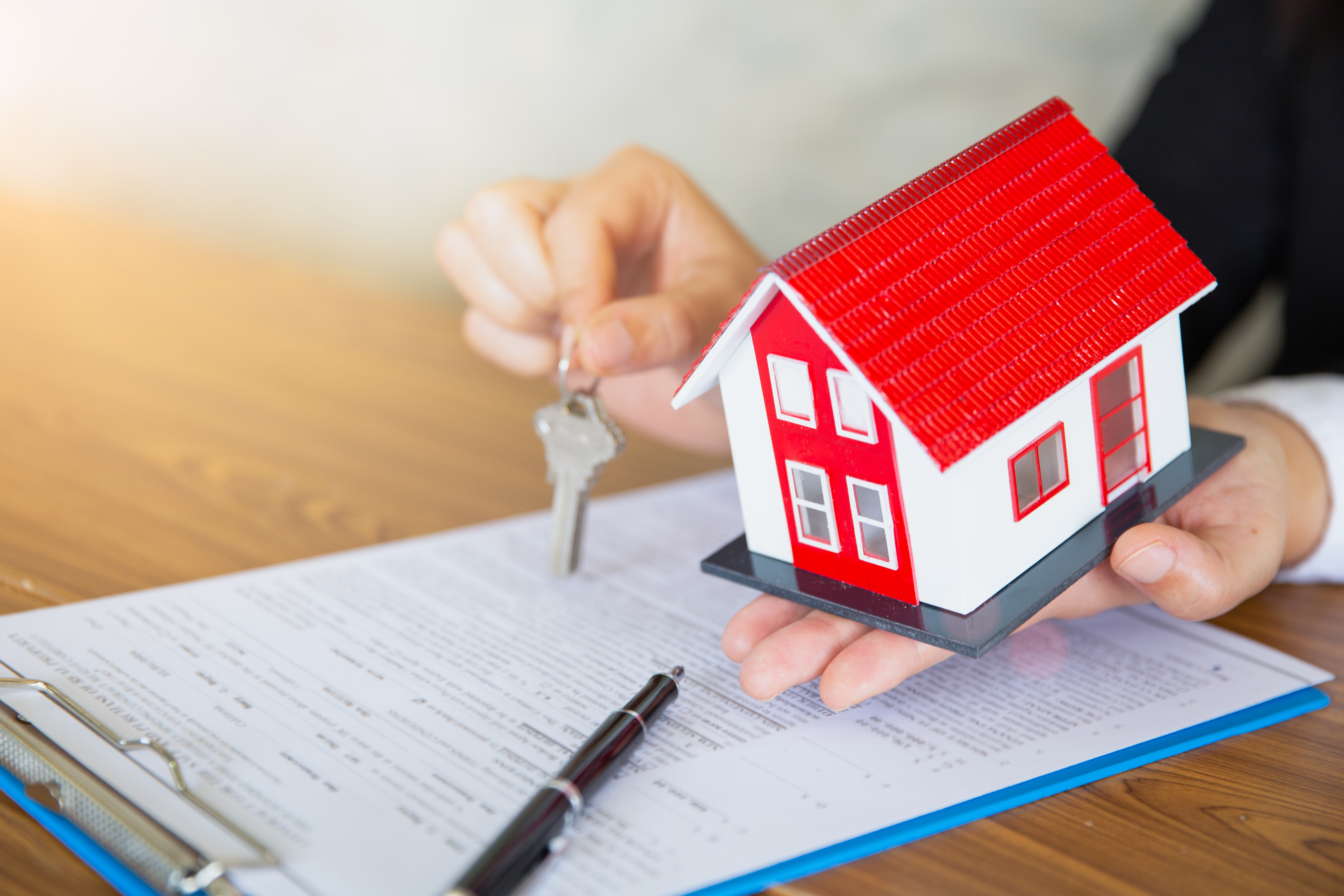 Hand holding plastic house and house keys