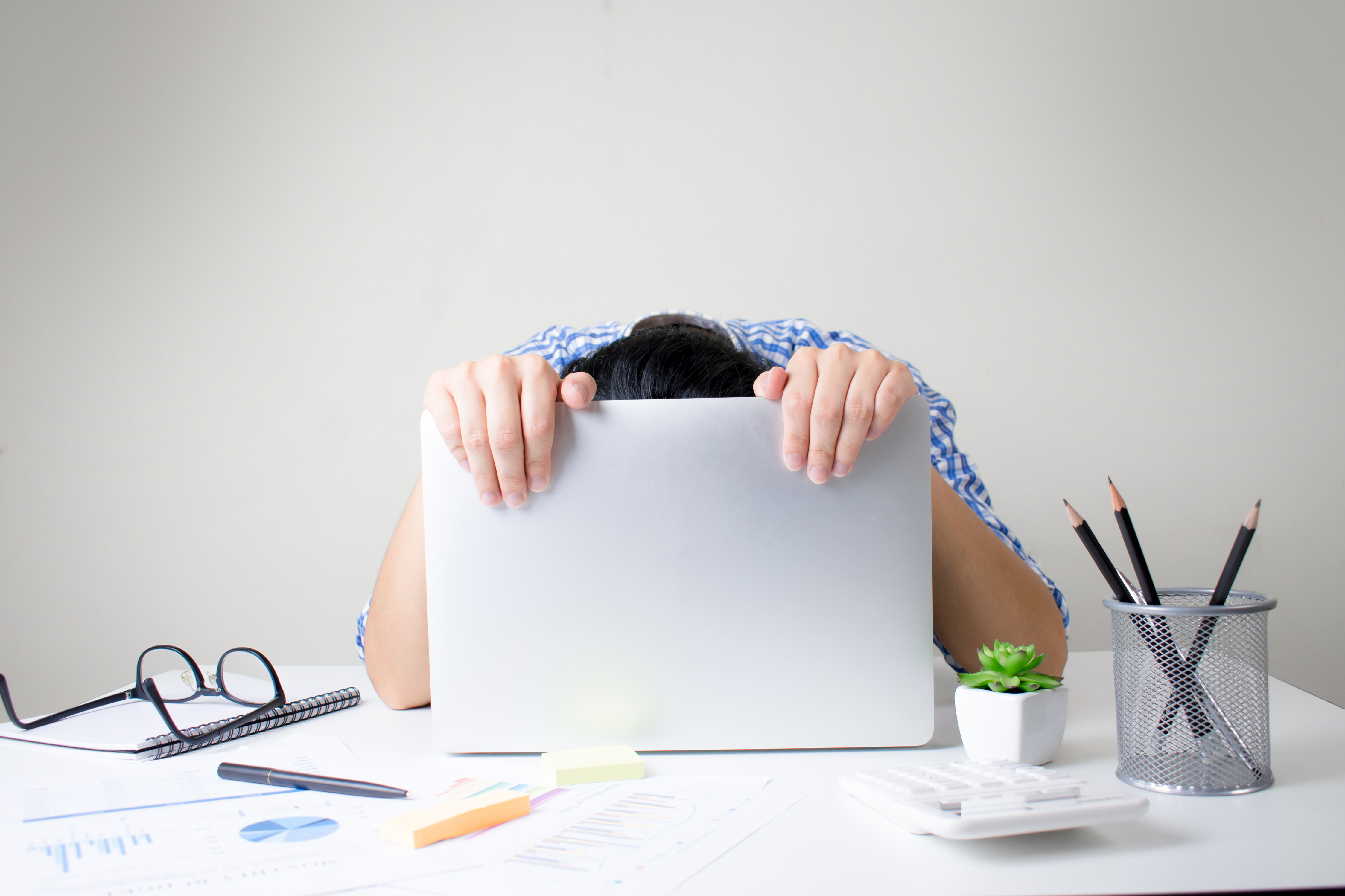 Person hanging their head behind a laptop screen