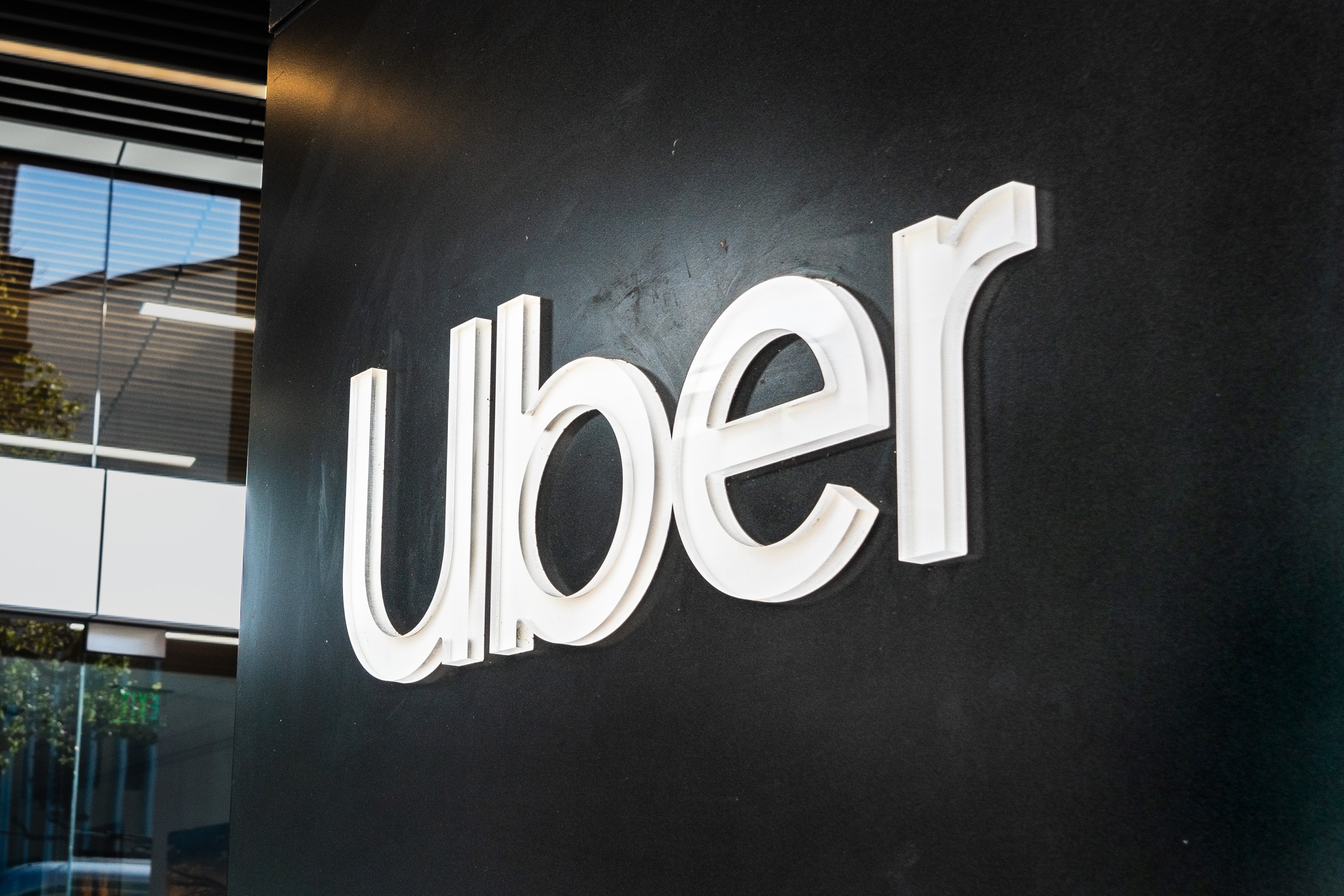 "Uber" in white letters, written on a black wall in what looks like the lobby of their office.