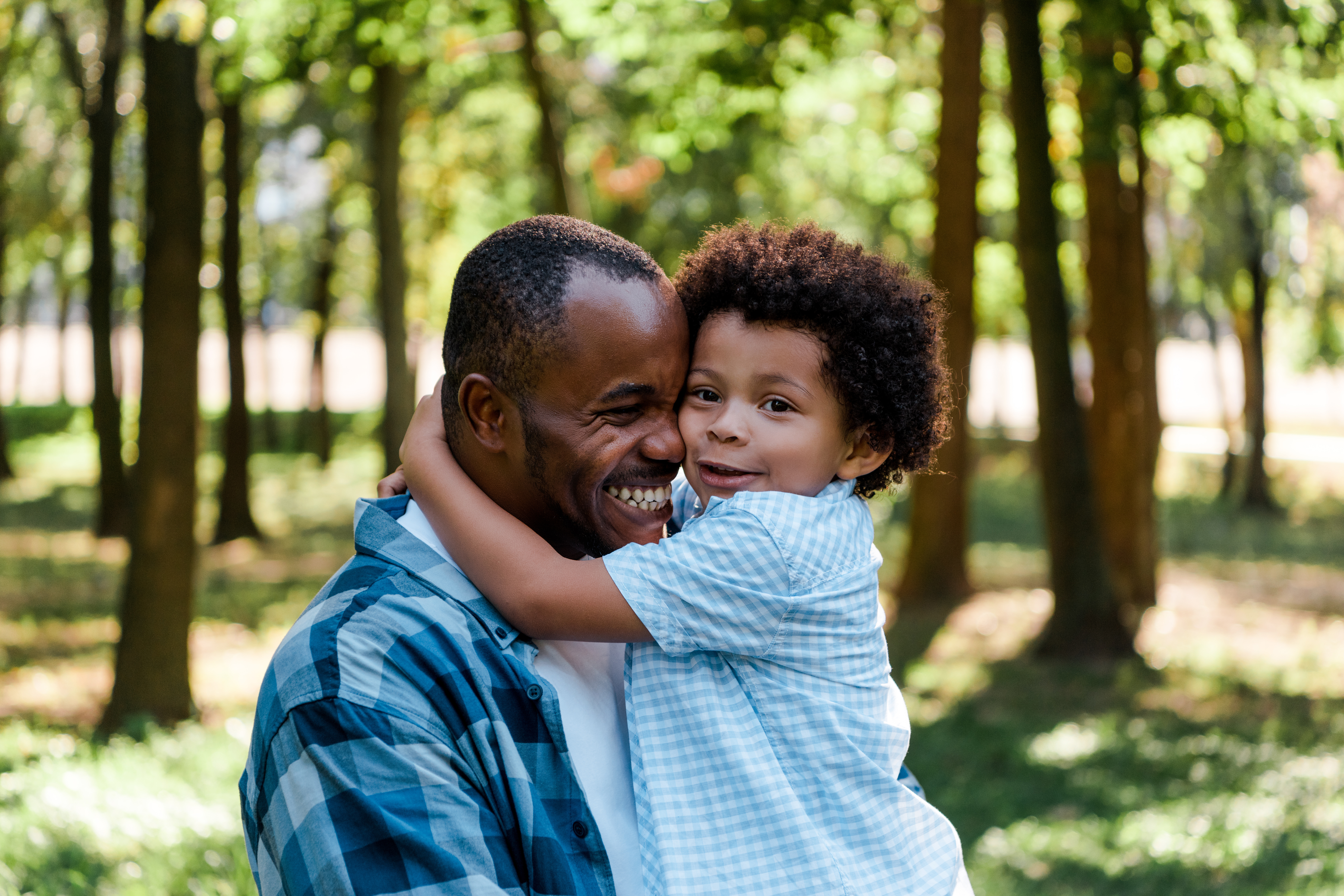 Dad holding child, smiling, child's arms around dad's neck