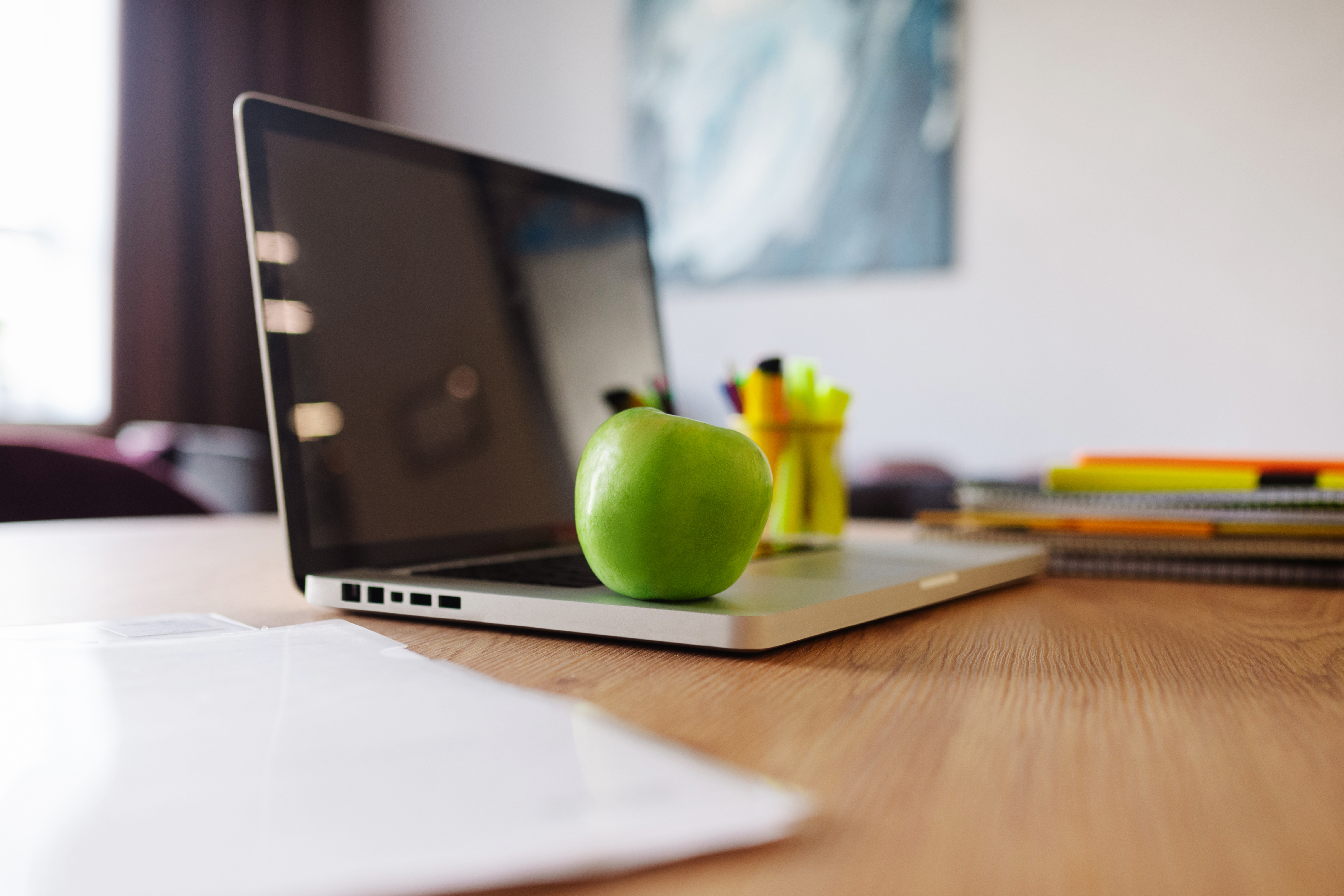 Laptop computer with green apple ; healthy snack at work