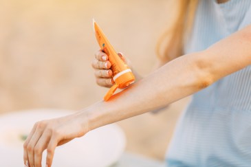 Woman putting sunscreen on arm