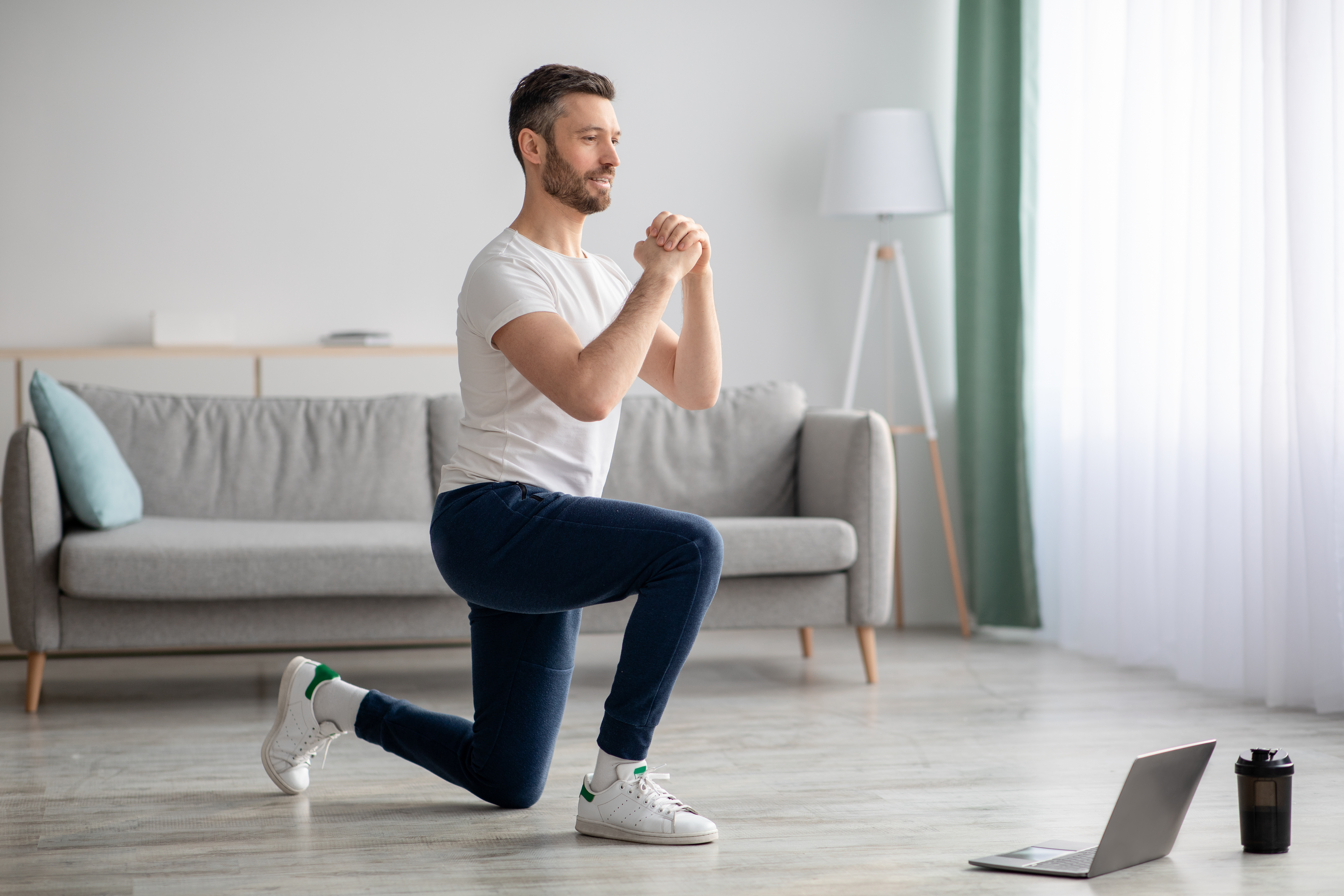 Man stretching with computer open; online fitness