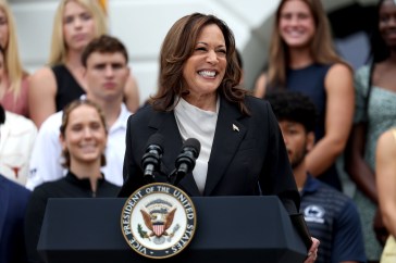 Kamala Harris smiling at a podium, addressing a crowd of supporters.