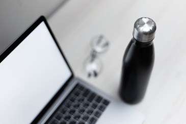 A reusable water bottle next to a laptop