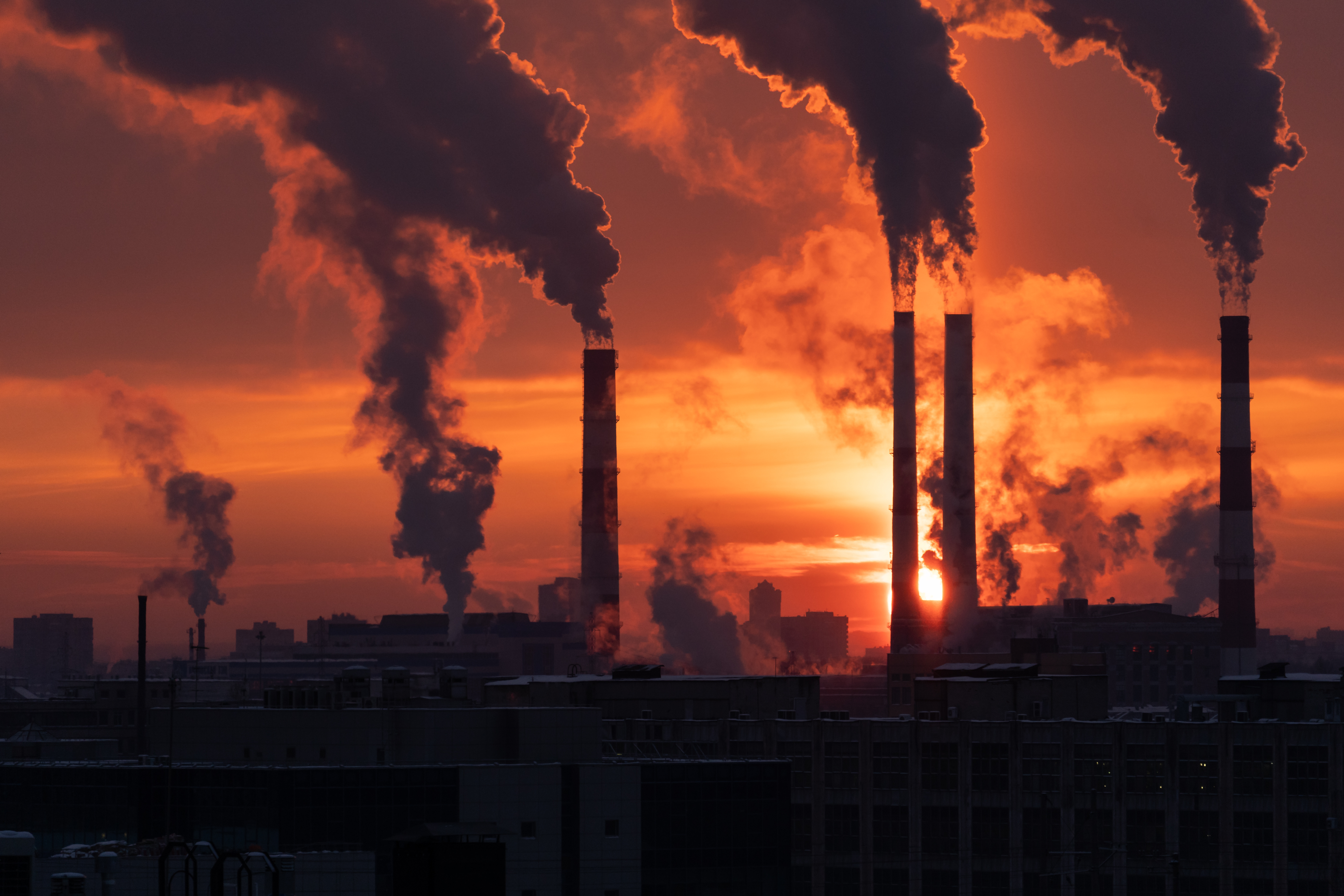 Smoke emitting from smokestack pipes during sunset.