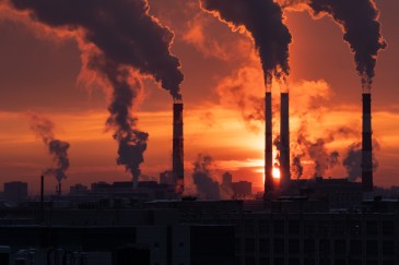 Smoke emitting from smokestack pipes during sunset.