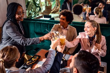 Employees sitting at restaurant table, cheers, toast, happy