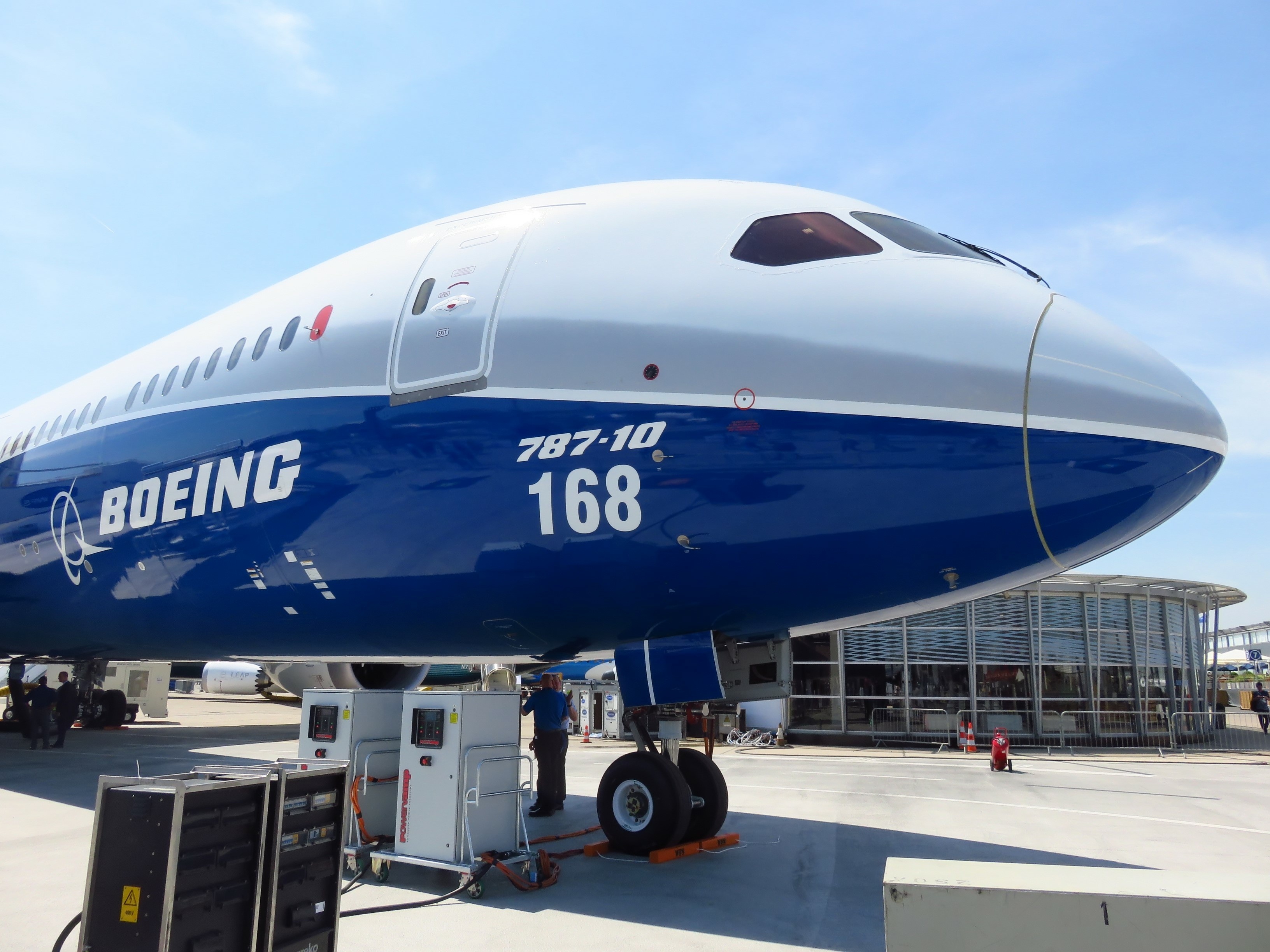 Boeing 787 plane outside of airport; a worker under the plane