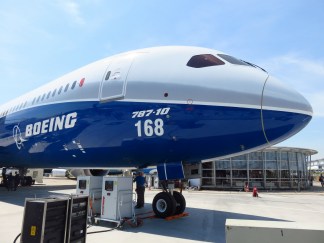Boeing 787 plane outside of airport; a worker under the plane