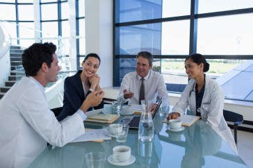 Group of people in meeting; doctors and people in business wear; smiling