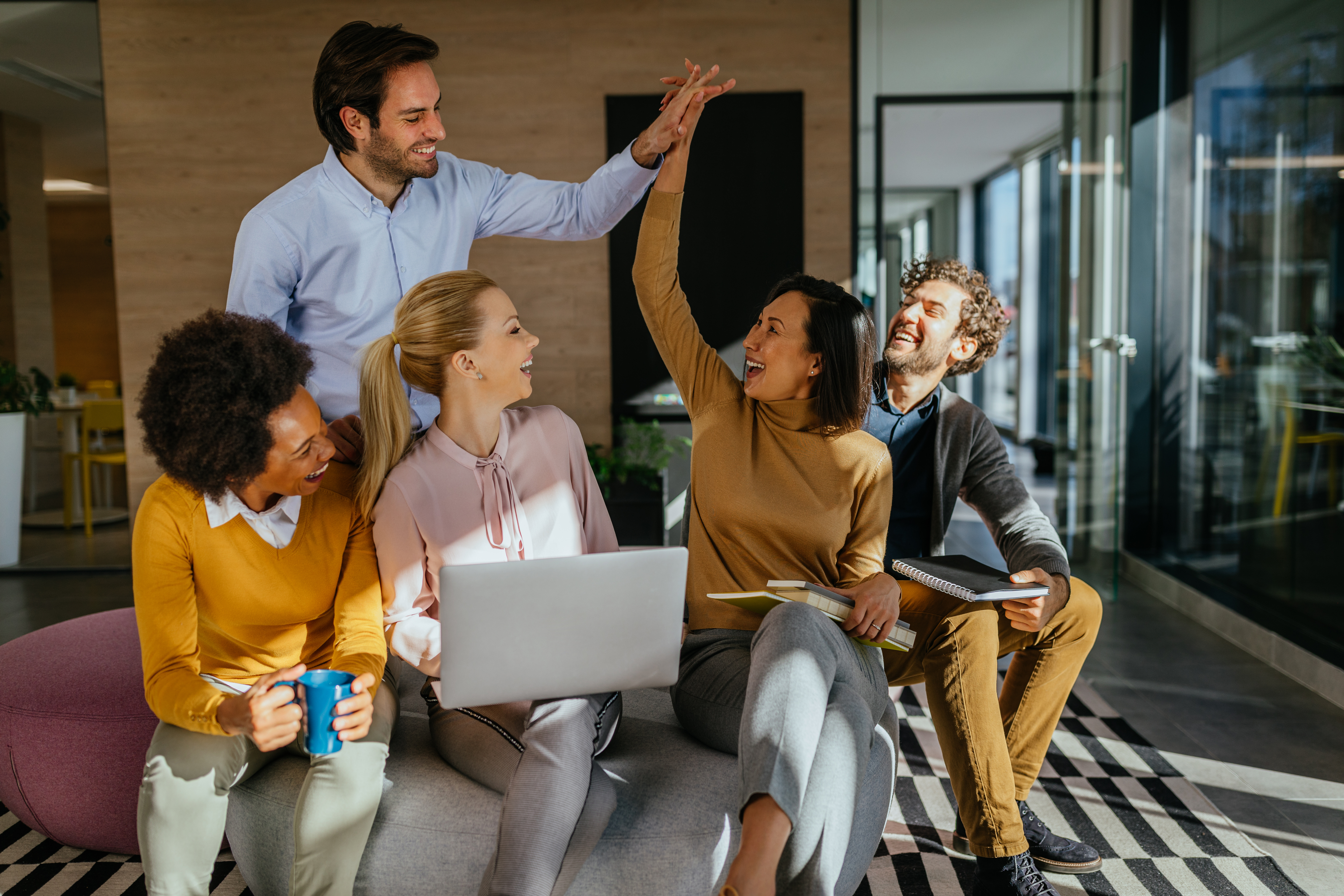 Group of employees working together, high-fiving each other, smiling