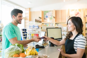 Man handing cashier credit card for groceries, paying