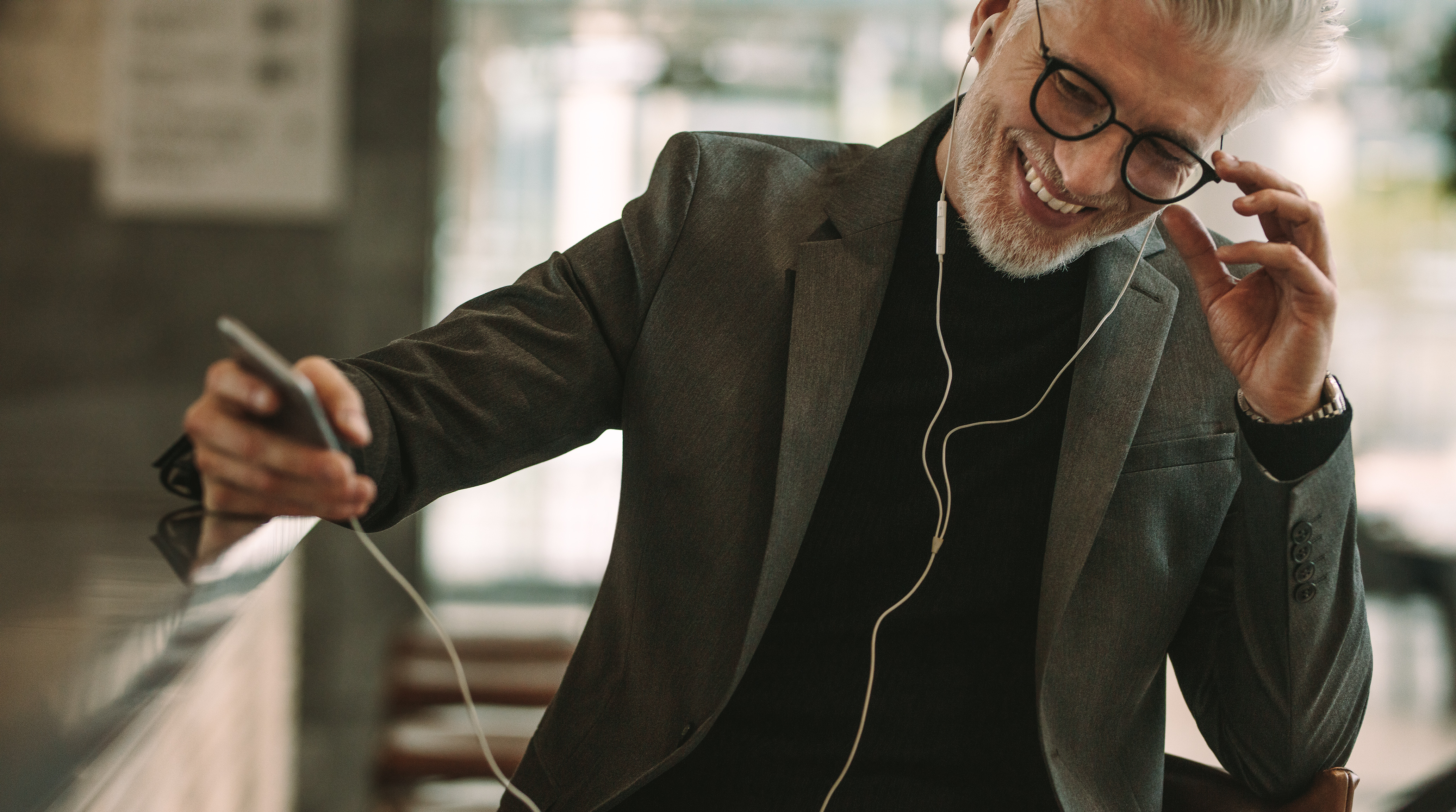 Man listening to music on phone and headphones, smiling