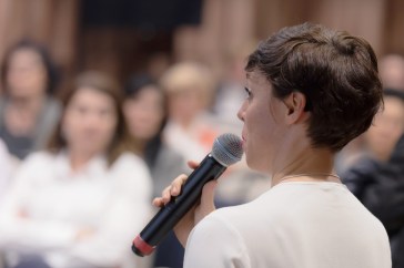 Woman holding microphone speaking on stage