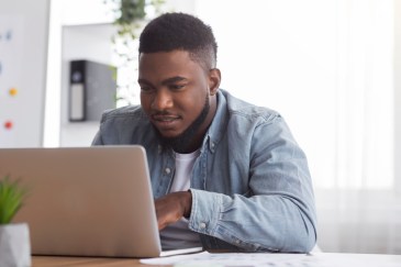 Man working on laptop computer, face close to the screen