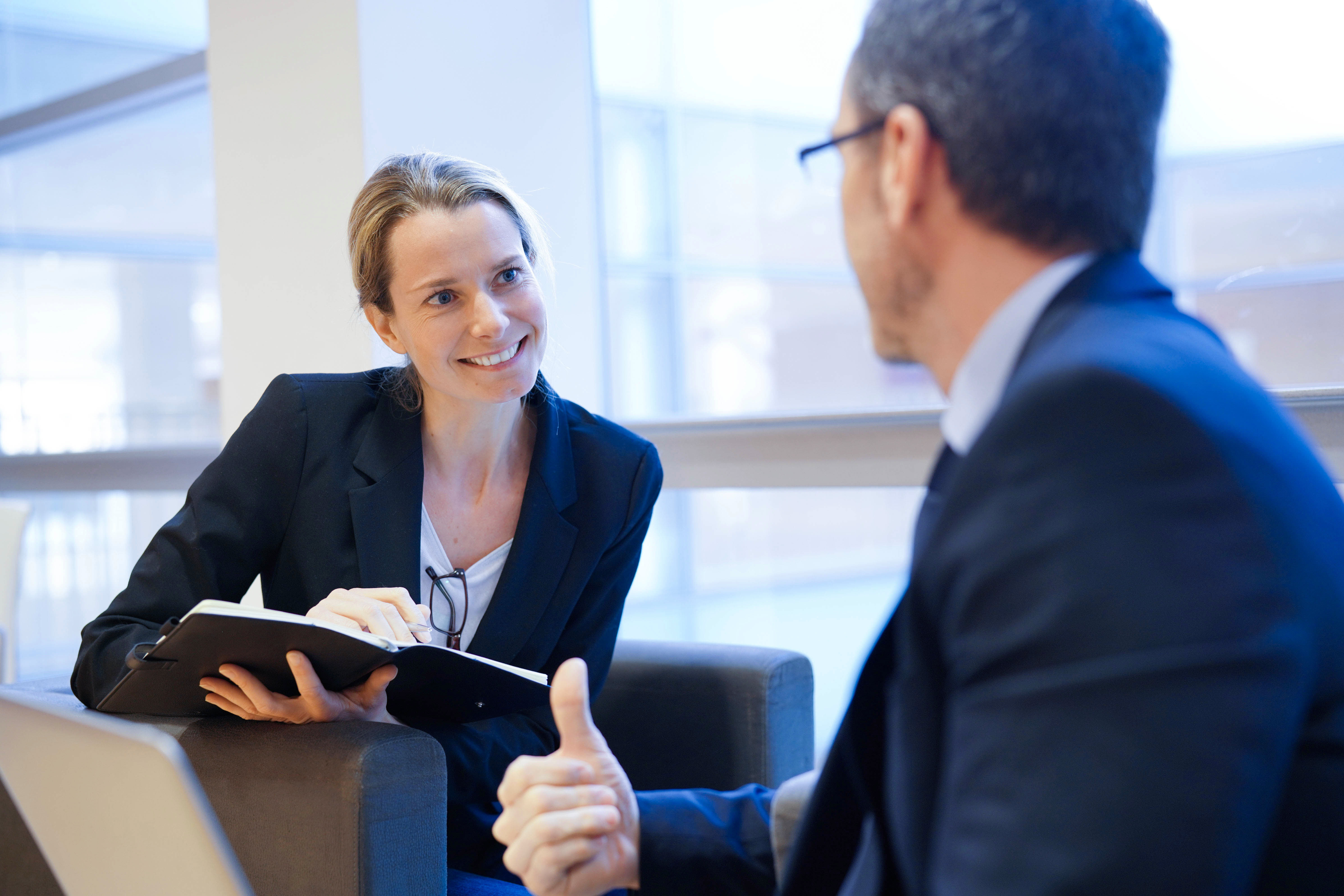 Woman talking with man, smiling, writing in notebook