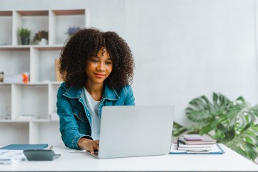Woman smiling, looking at laptop