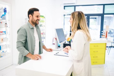 Man standing talking with pharmacist at counter