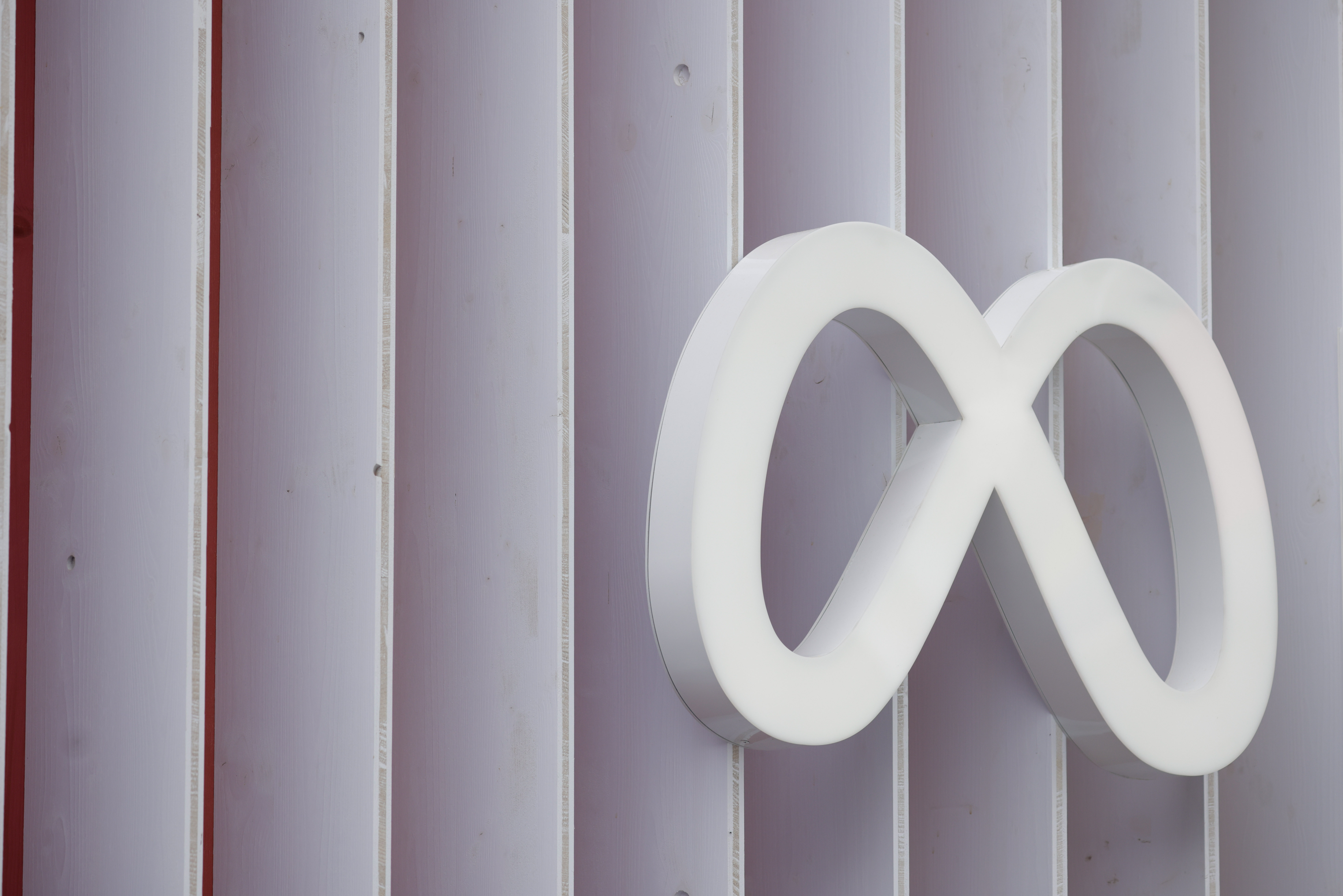 Meta logo (a white infinity loop) on the side of a paneled building.