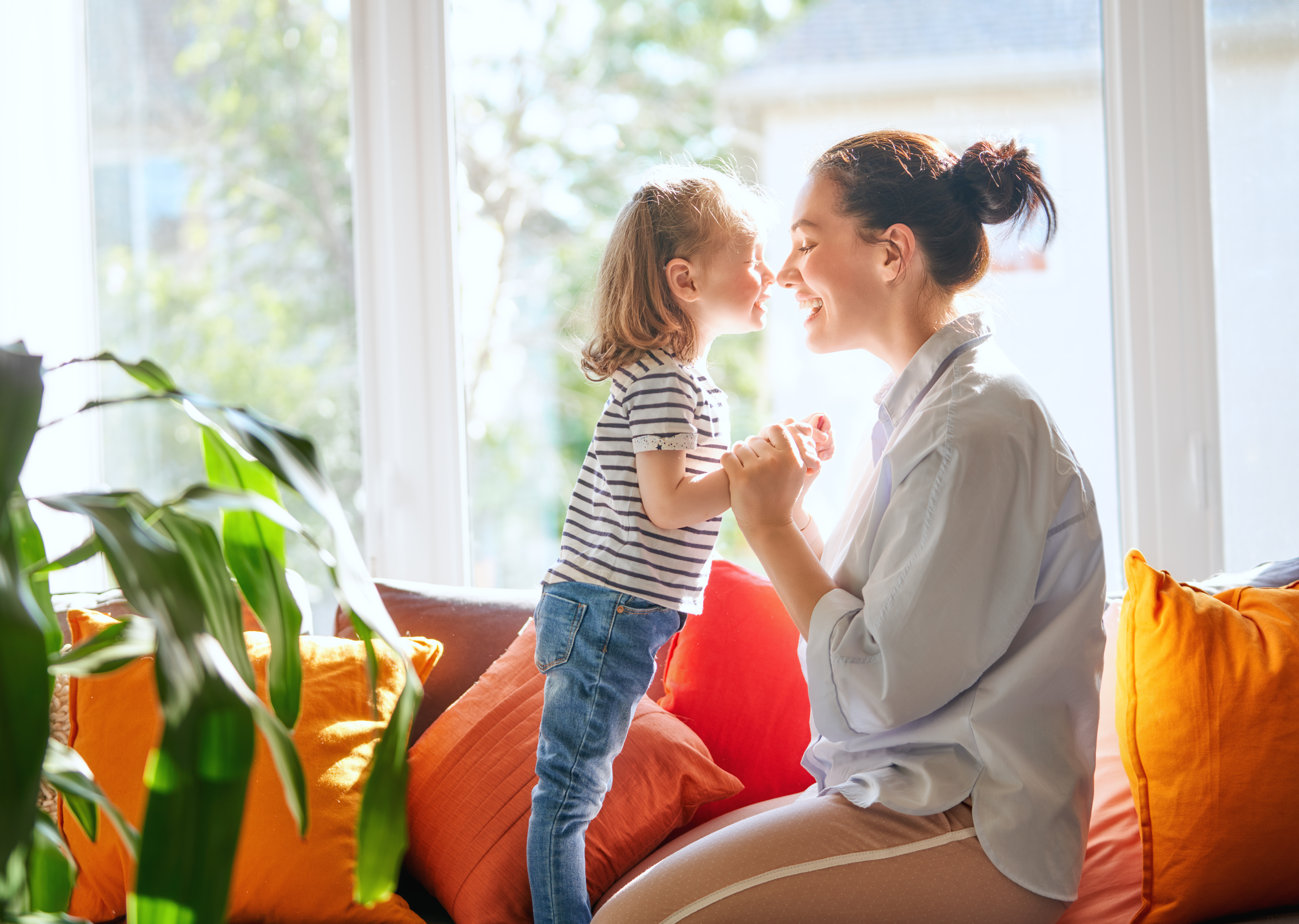 Mother and daughter nose to nose sitting next to window