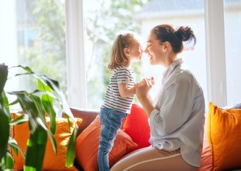 Mother and daughter nose to nose sitting next to window